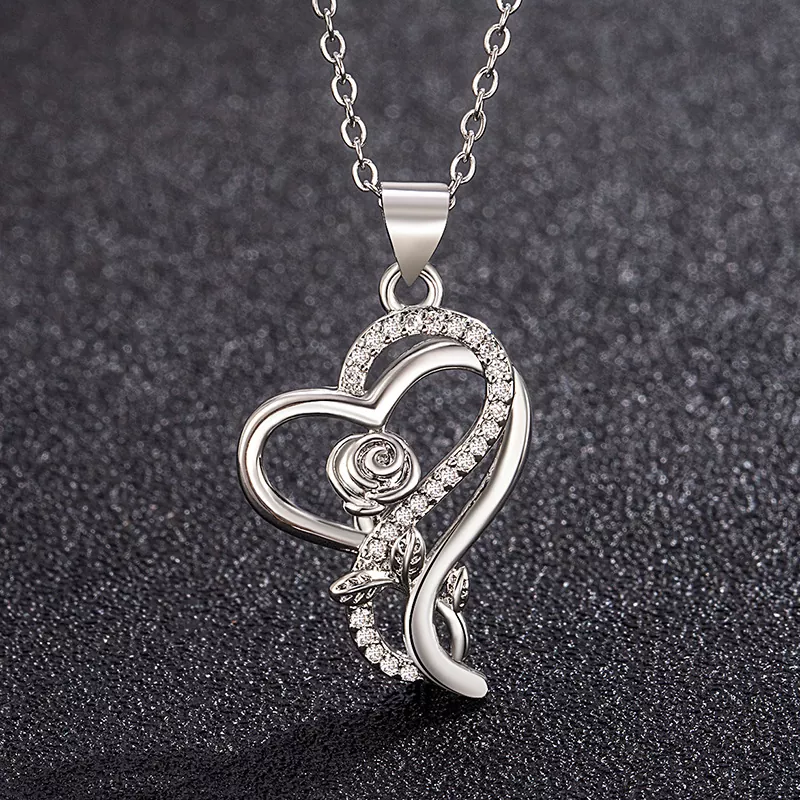 Stainless steel heart-shaped pendant with rose and cubic zirconia details, hanging on a silver-tone chain, showcased on a black glitter background for wholesale jewelry promotion – yanluojewelry.
