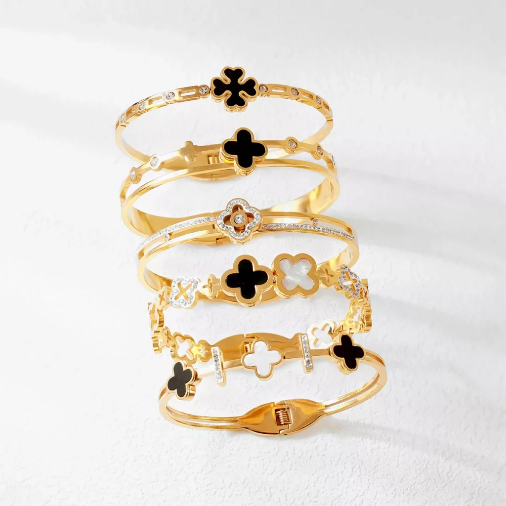 Stack of five gold stainless steel bangles with black and white enamel four-leaf motifs – Yanluo Jewelry wholesale display