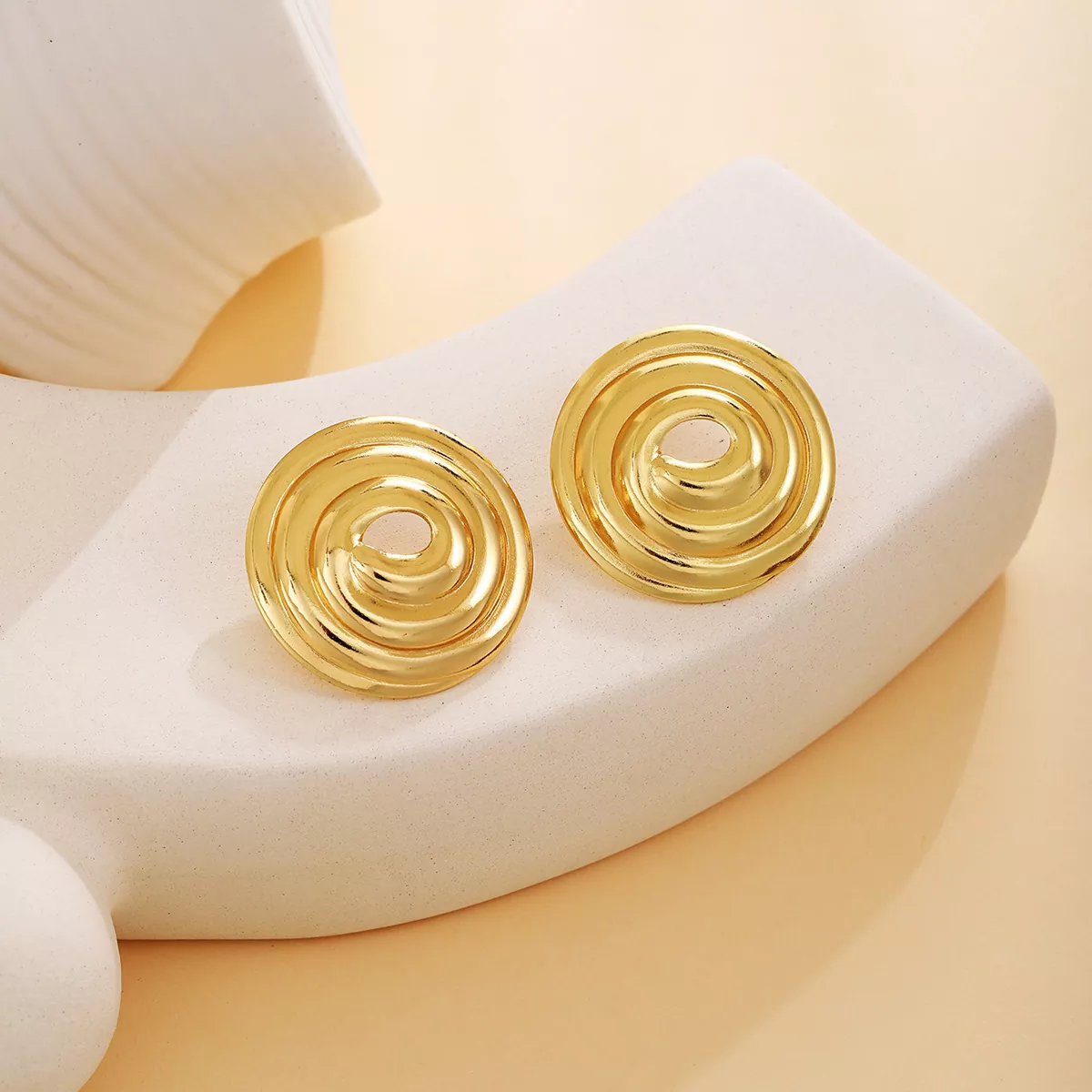A pair of spiral gold stainless steel earrings with a glossy finish, designed for modern fashion wholesale collections.