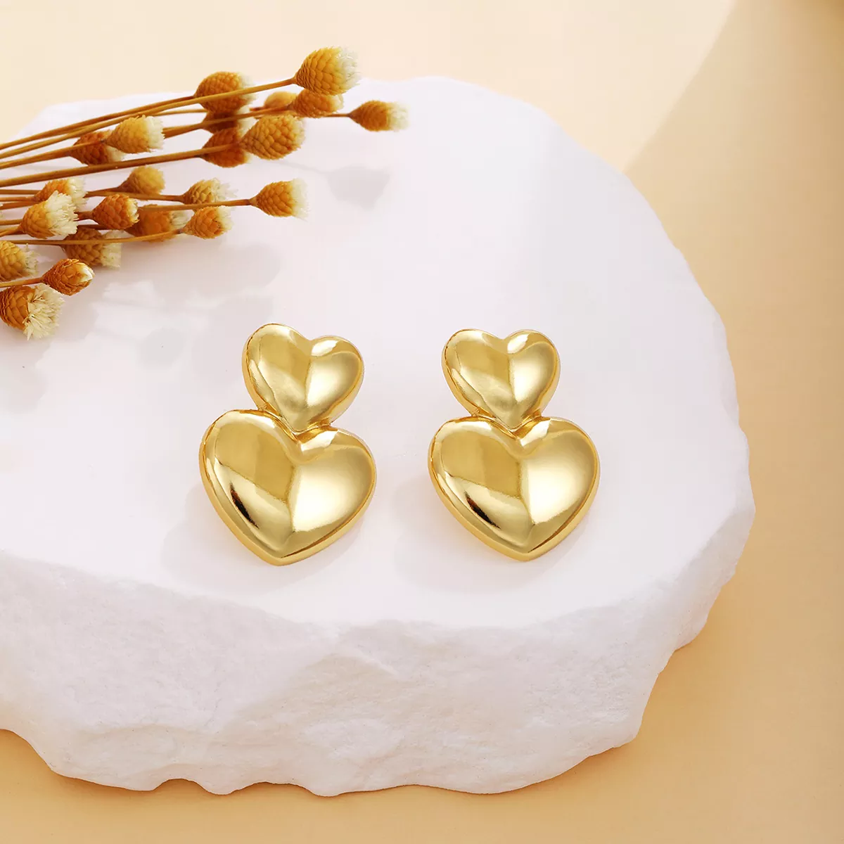 Double heart gold stainless steel earrings on white stone display, romantic design, wholesale supplier