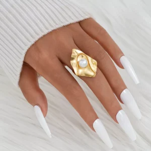 Gold stainless steel ring with irregular folded design and pearl centerpiece, showcased on a model's hand; offered by a stainless steel jewelry wholesale supplier