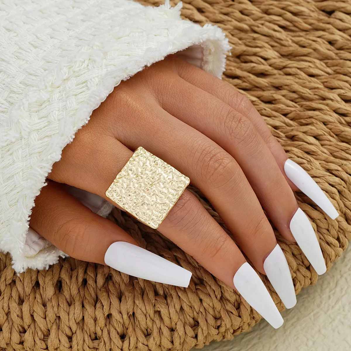 A gold square textured stainless steel ring, worn on a model's hand, suitable for wholesale and retail, showcasing a modern minimalist style.